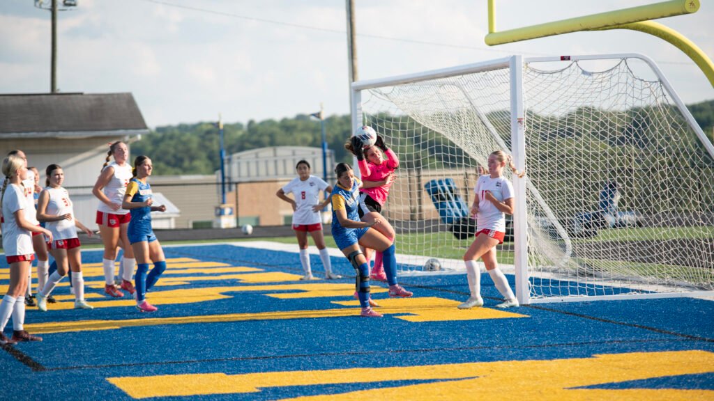 West Muskingum's Mikala Willet collides with the Lady Bishops goalie Izzy DeMattio as she makes a save.